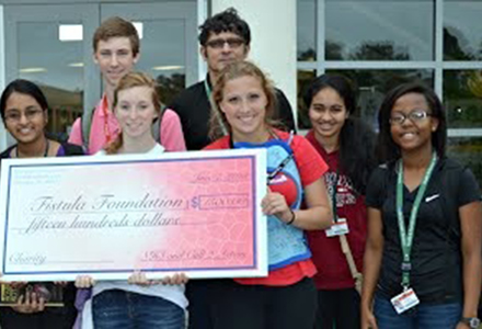 Seven students hold a large check for $1,500for the Fistula Foundation.