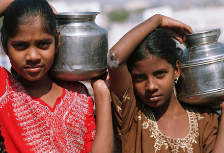 Girls carry water jugs in India