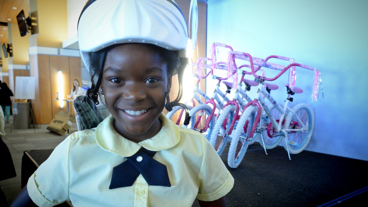 Global Scholars Academy student Rayne Platt wears a bicycle helmet in front of a row of bicycles.