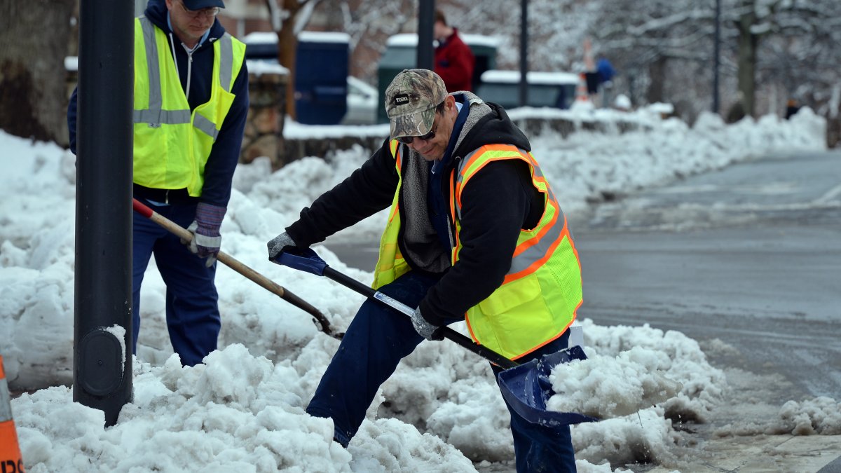 University grounds department workmen clear snow from a sidewalk