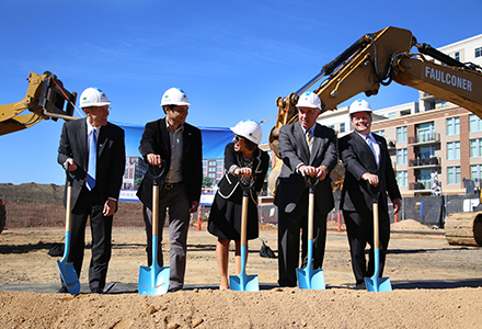 A group of five people with shovels break ground.