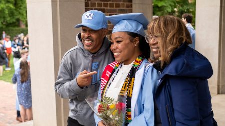 A graduate poses for a photo with their family.