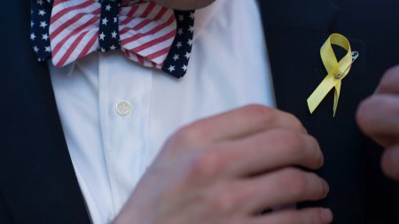 Yellow ribbon sits on a man's jacket.