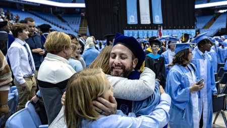 A graduate hugs their family.
