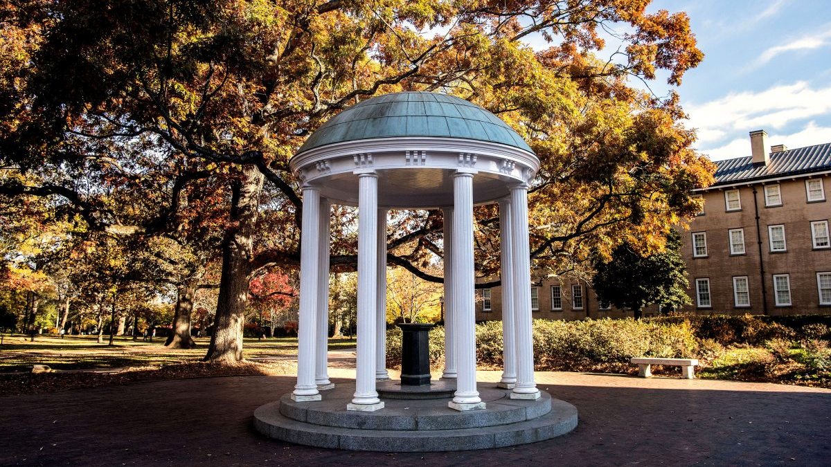 Old Well surrounded by trees with leaves changing color during fall.
