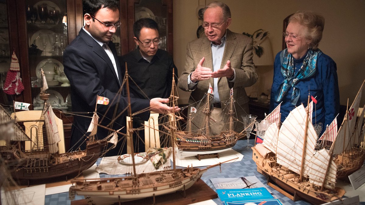 People are standing behind model ships