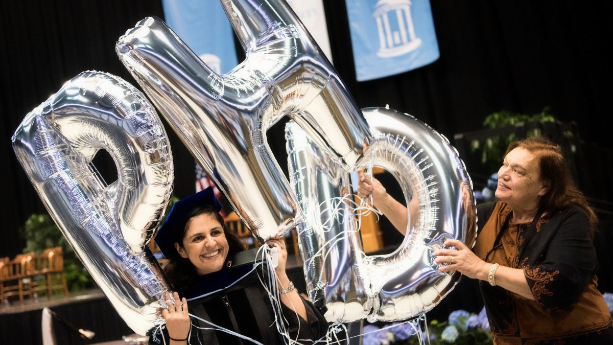Doctoral Hooding candidates hold balloons spelling P.H.D.