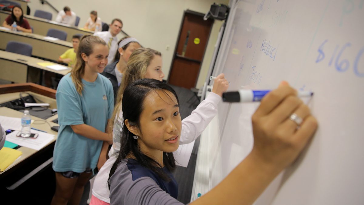Students writing on a whiteboard.