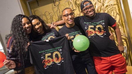 Four students hold BSM 50th anniversary shirts
