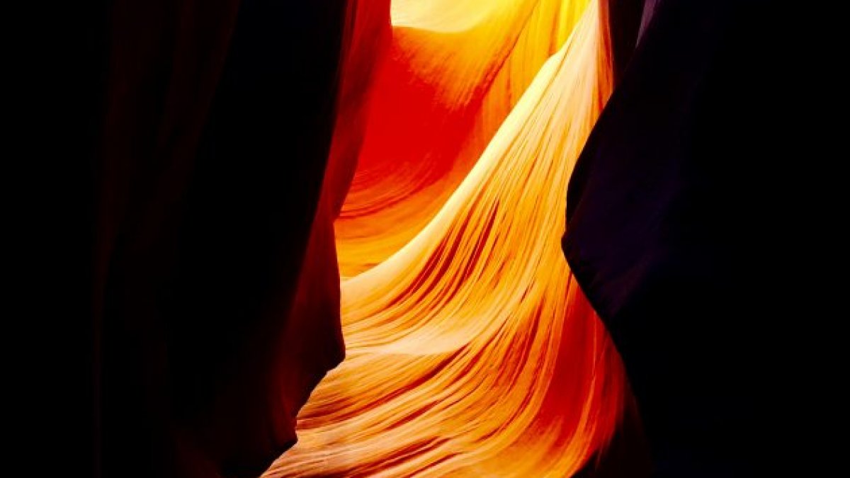 Light streaming through a black canyon lights up in yellow and orange