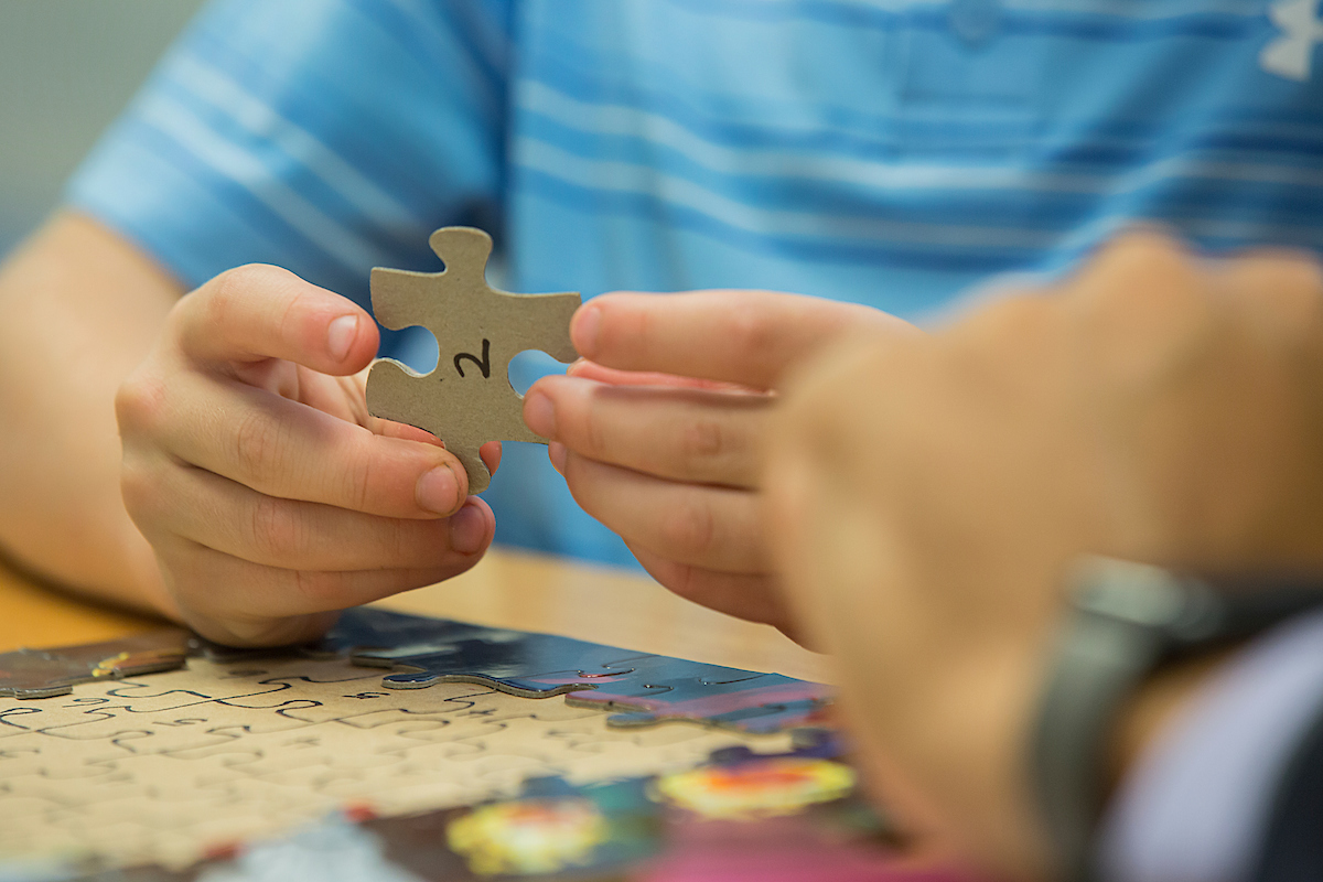 Young boy holds a puzzle piece.