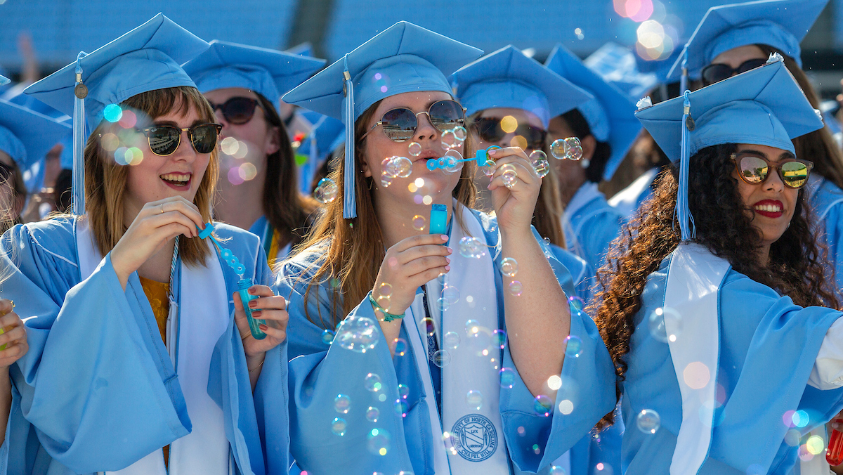 Graduates blow bubbles at graduation.