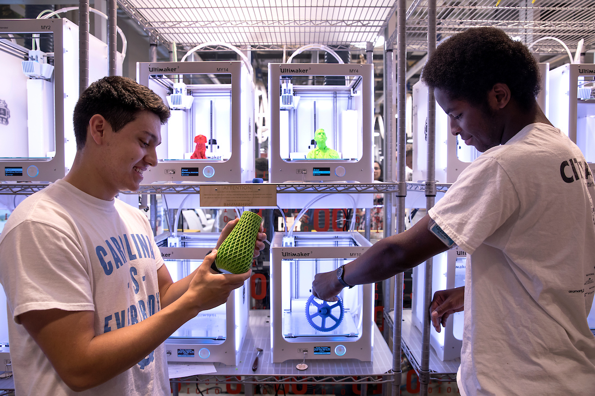 Two students use a 3D printer.