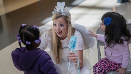A student dressed up like a toothfairy talks with young children.