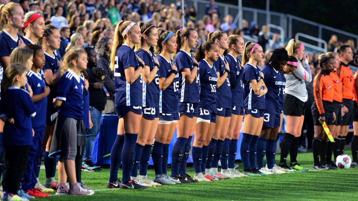 Members of the women's soccer team stand for the national anthem
