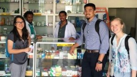Students stand near a pharmacy counter.