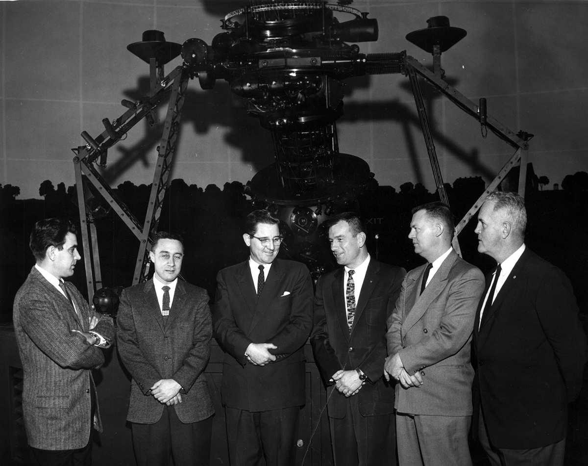 Various Astronauts and University figures pose by Morehead Planetarium telescope.