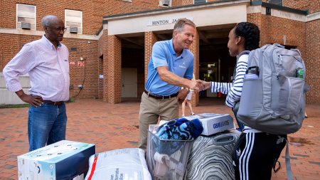 Kevin Guskiewicz shakes hands with students during move in.
