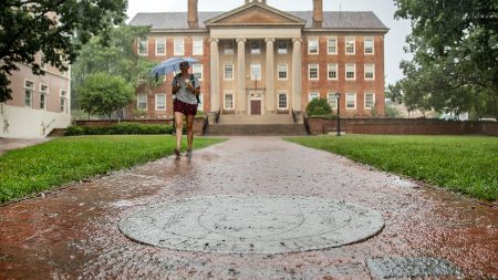 A student walks in the rain near South Building.