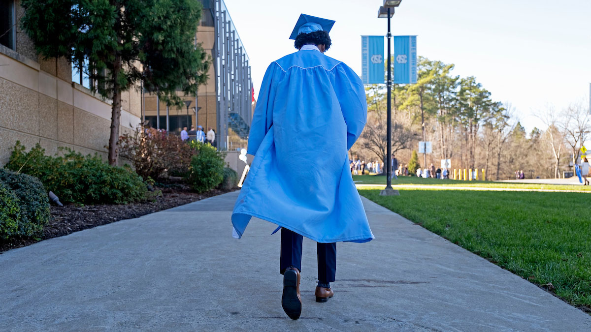 A graduate walks toward the Smith Center