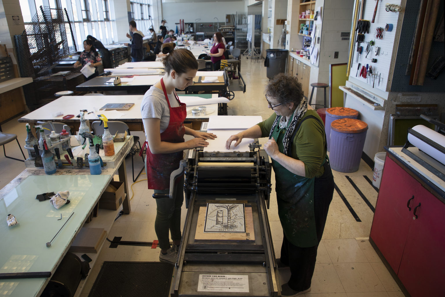 Two women work on a letterpress.