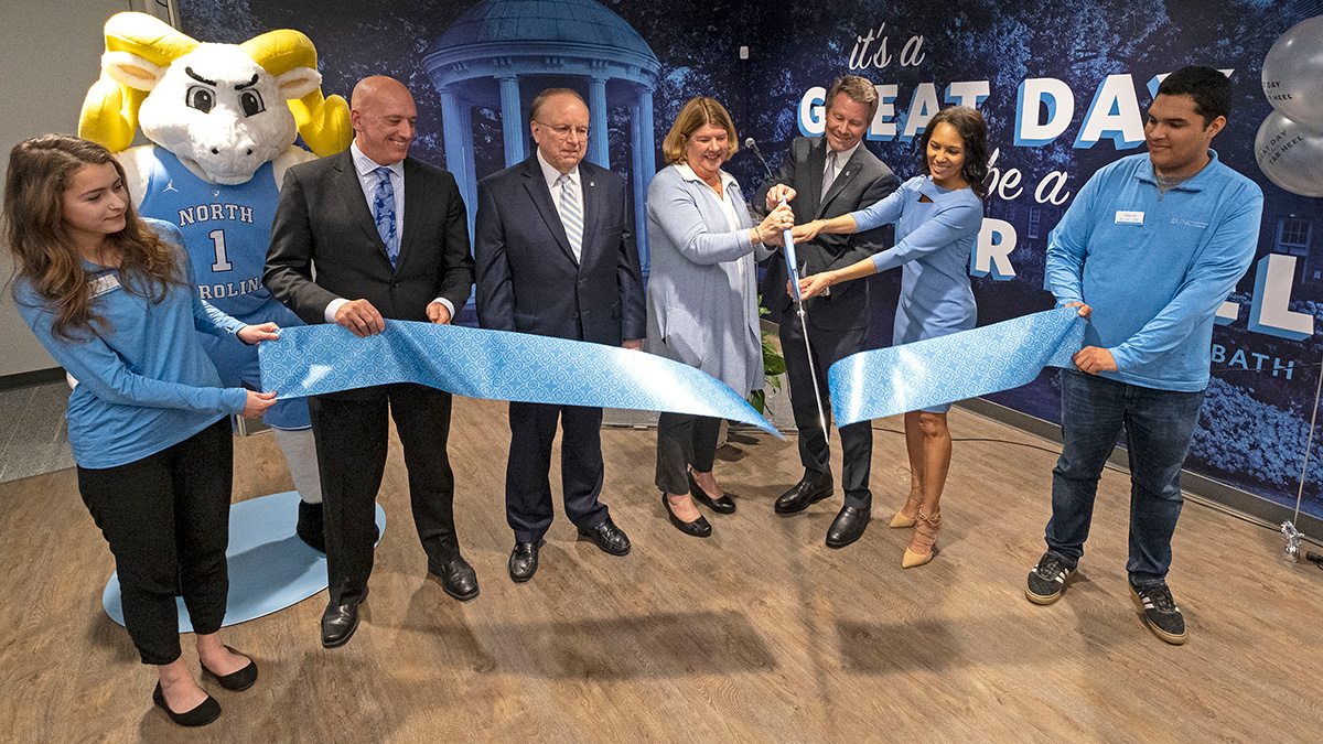 Seven people cut a ribbon at the UNC Visitors Center.
