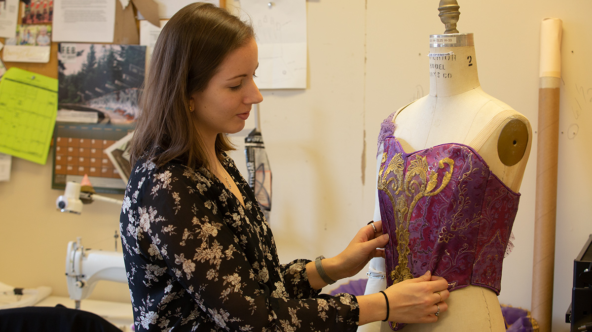 Jane Reichard adjusts a dress on a model.