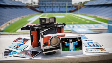 A polariod camera in Kenan Stadium with photos around it.