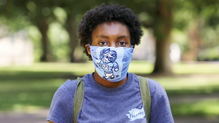 A female student wears a mask with a Rameses mascot on it.