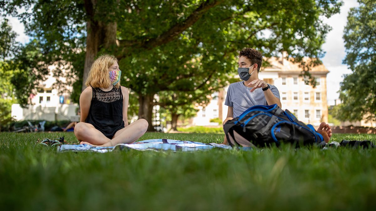 Two students sit on Polk Place.
