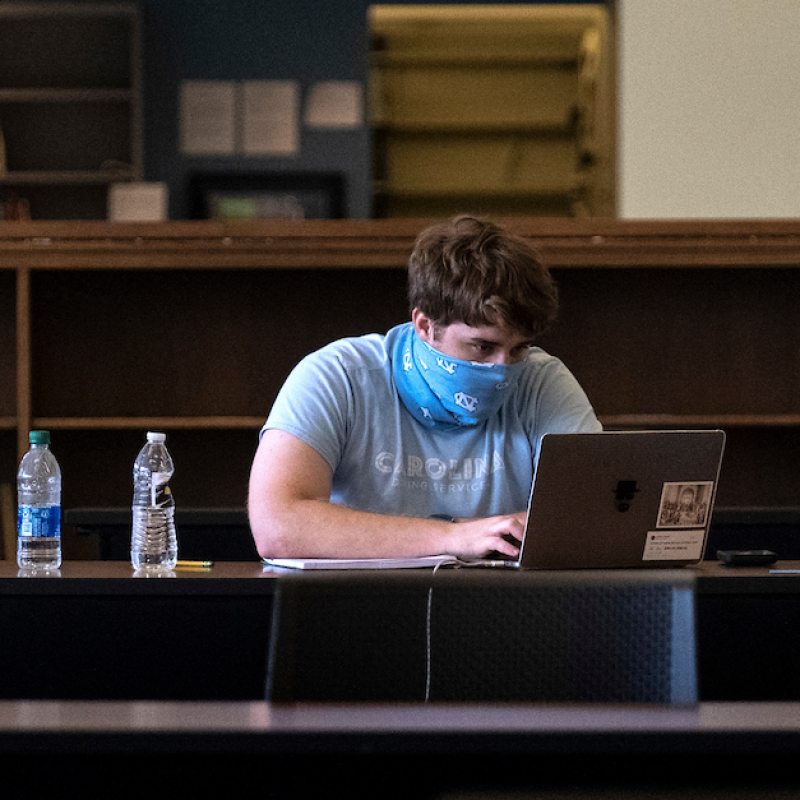 A student works on a laptop in the library,
