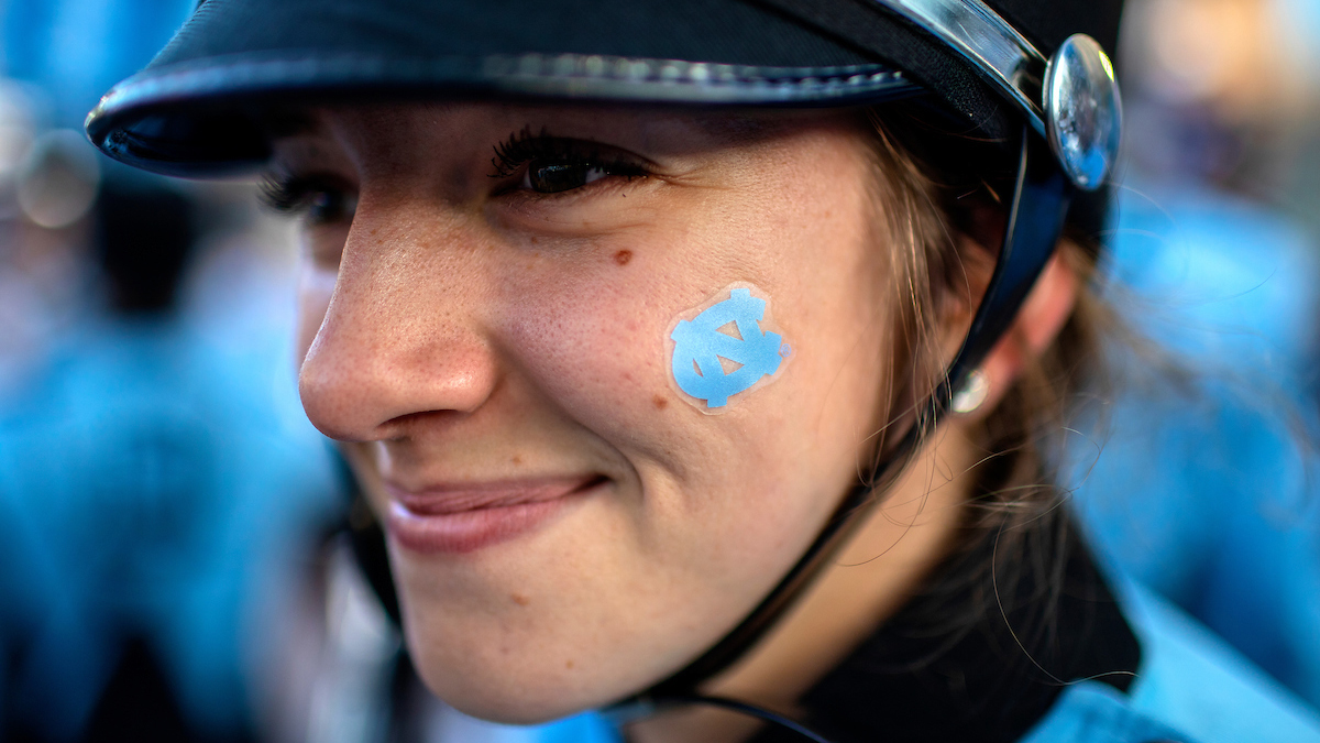 A band member with a UNC logo on her cheek.