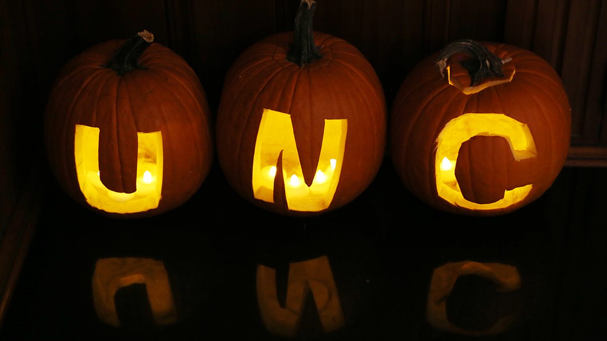 Three pumpkins with UNC carved in them.
