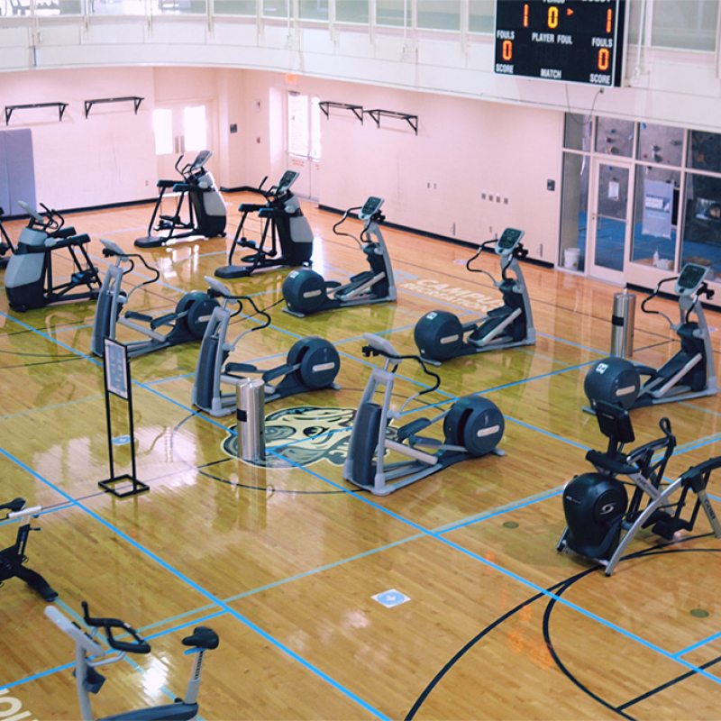 A basketball court with cardio workout equipment spread out.