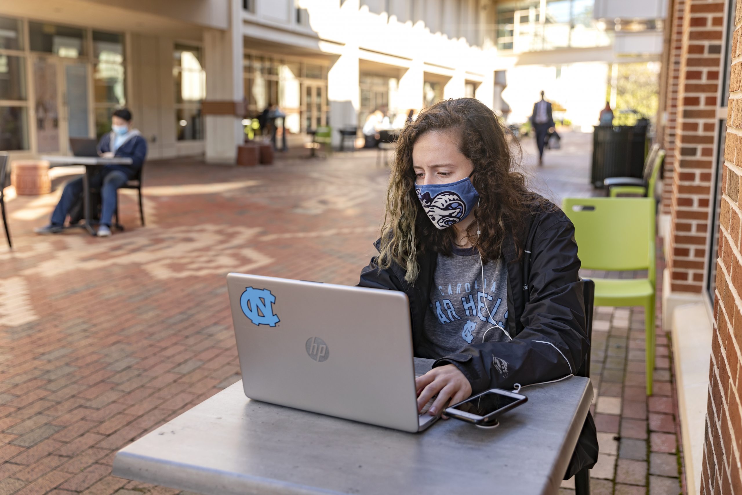 A student works on a laptop near the Carolina Union.