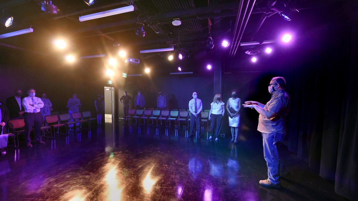 A group of people stand in a performance area in the new facility.