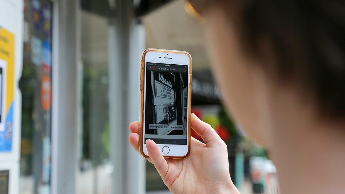 A person uses their phone to access the 'ARt Walk on Franklin' website.