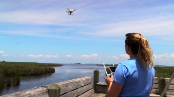 A woman flies a drone over water