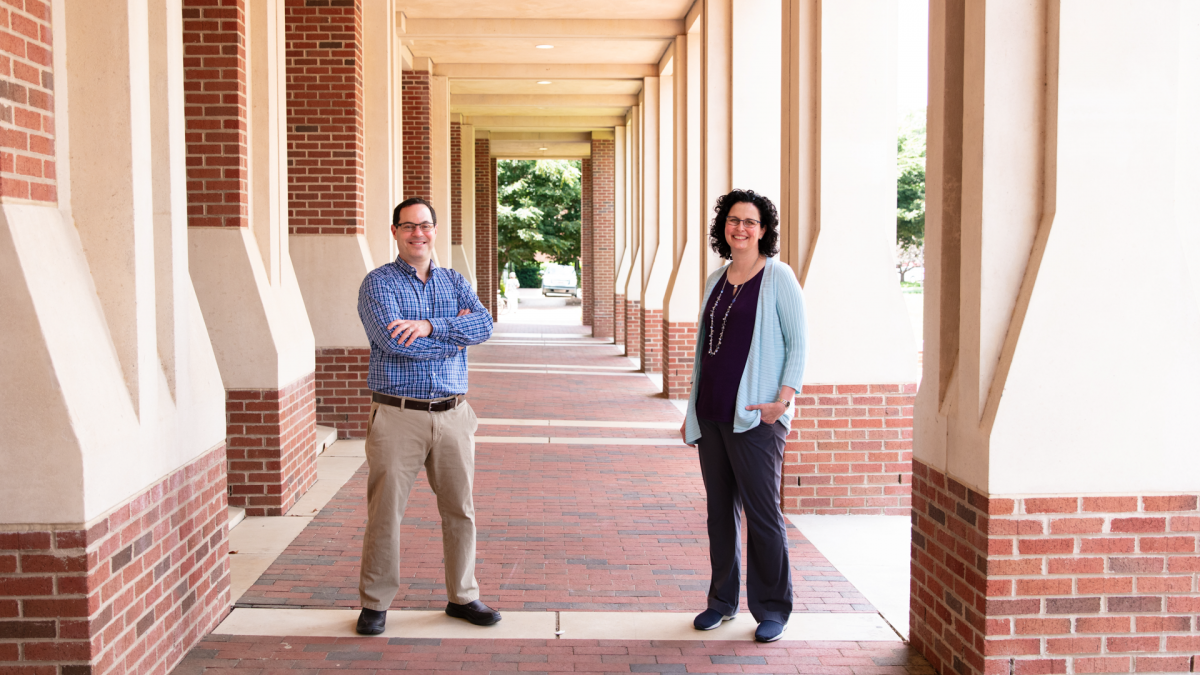 Brian Strahl and Samantha Pattenden stand outside by an academic building.