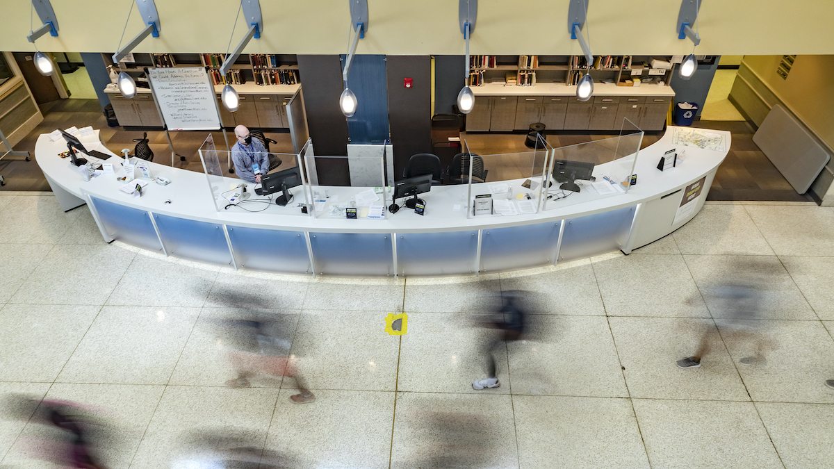 Students walk past the desk of Davis Library.