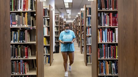 A student walking in the library stacks.