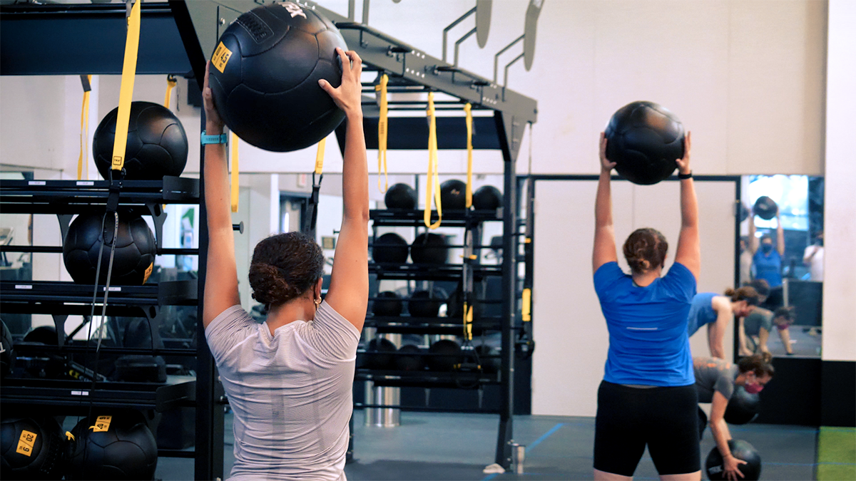 A person holds a medicine ball above their head.