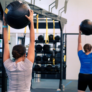 A person holds a medicine ball above their head.