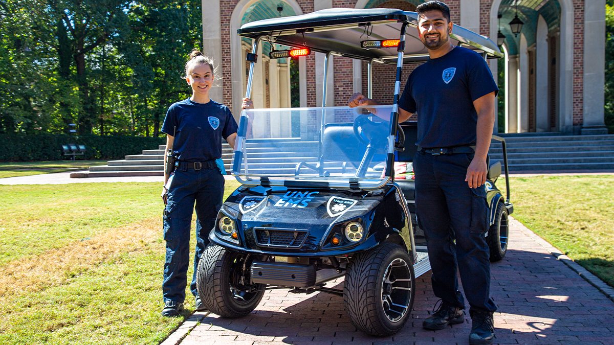 Sara Torzone and Ishan Khosla standing next to a golf cart.