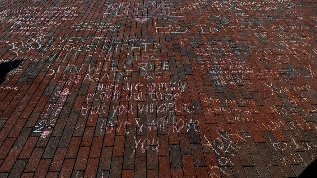Messages of hope written in chalk on brick sidewalk