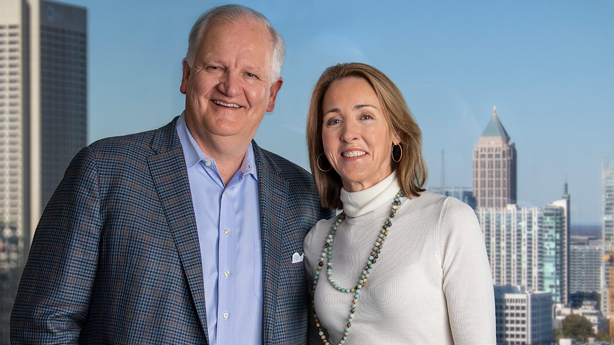 Jim Kerr and Fance Kerr pose for a photo in front of the Charlotte skyline.