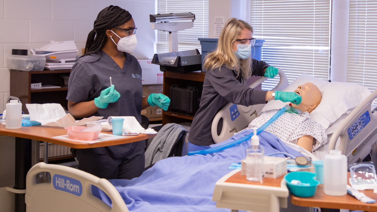 Nursing students practice working with a patient in a simulated situation.