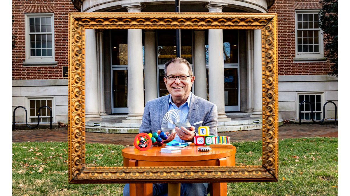 Keith Sawyer outside the UNC School of Education with creativity toys on a table.