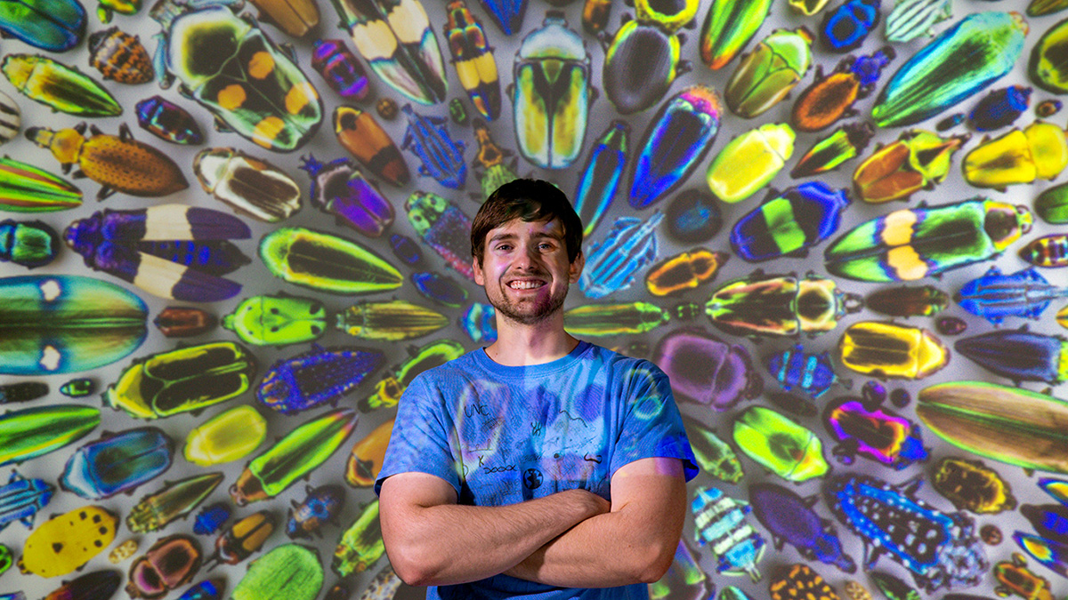 Brian Lerch standing in front of a projection of beetles.
