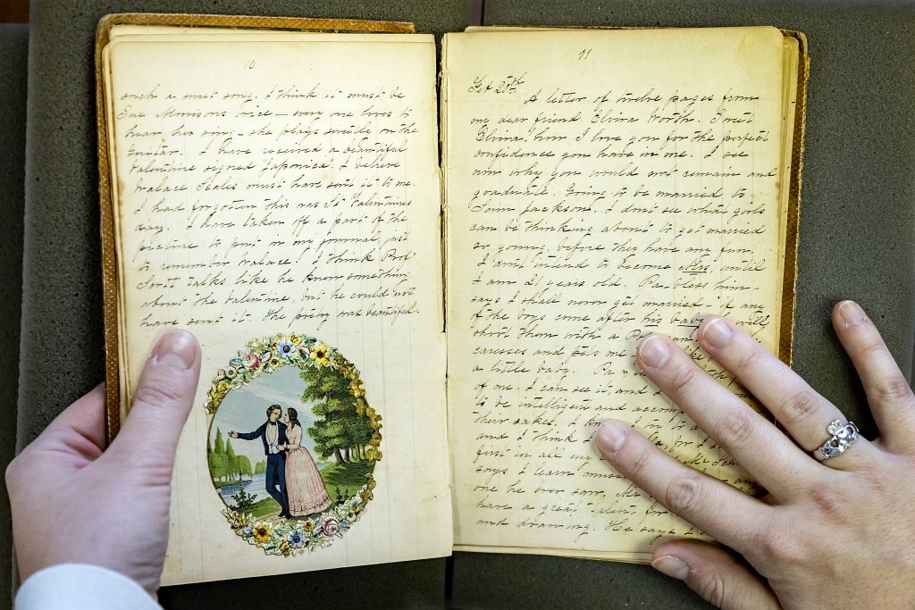 A diary from the 19th century with a card cut out pasted onto a page